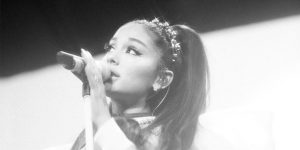 Cantora Ariana Grande segurando um microfone que está no pedestal