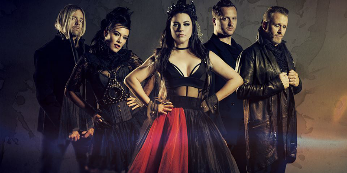 Banda Evanescence com trajes pretos. Amy Lee está com um vestido preto e vermelho