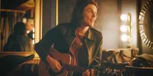 Cantor James Bay sentado em uma sala de espelhos com um violão