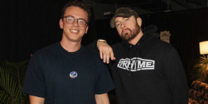 Logic de camiseta azul marinho e Eminem de moletom preto posando juntos para foto.