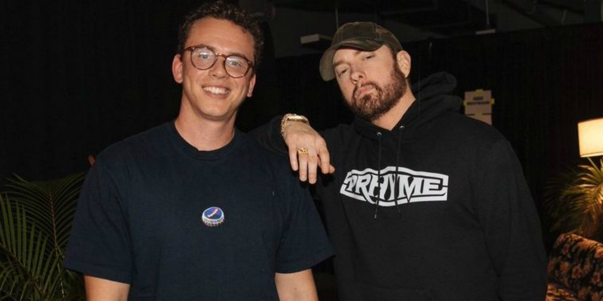 Logic de camiseta azul marinho e Eminem de moletom preto posando juntos para foto.