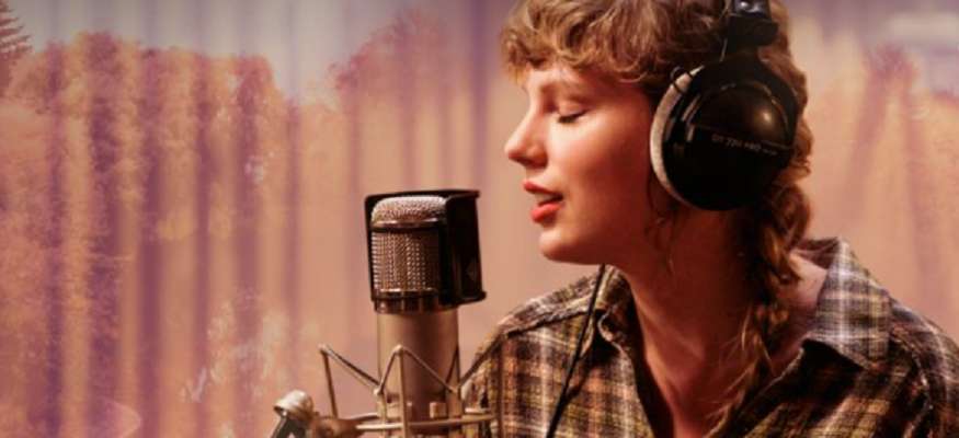 taylor swift em frente a um microfone em estudio cantando no especial do album folklore no disney plus