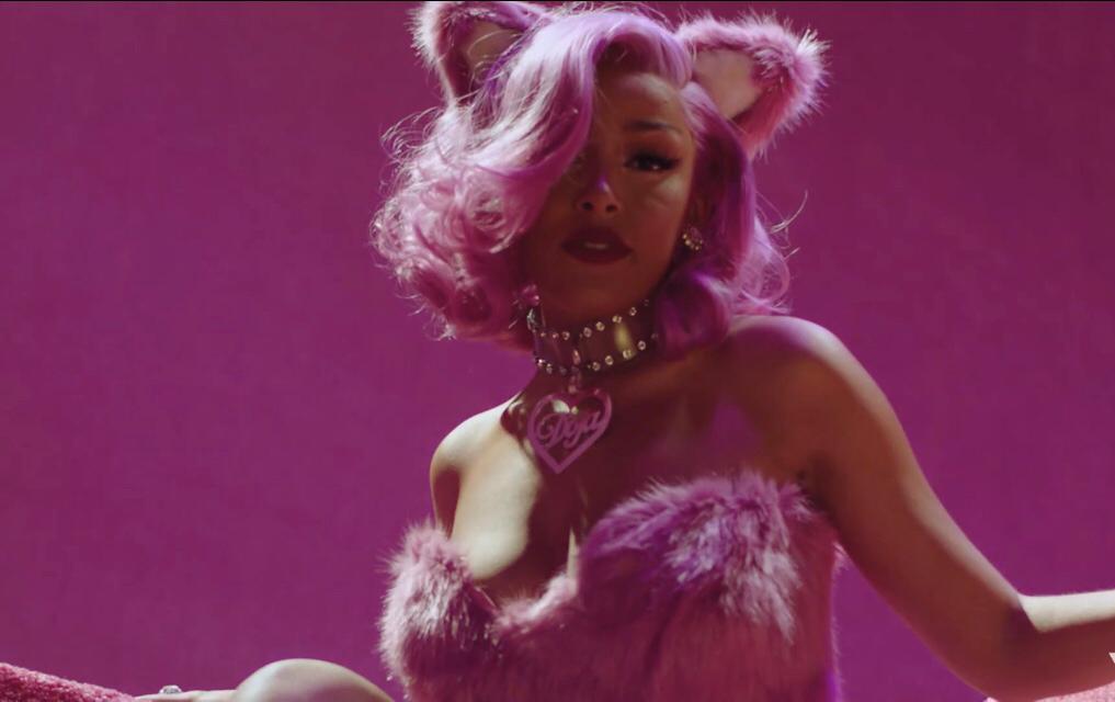 doja cat vestida de com um sutiã de pelúcia roxo, cabelo roxo e tiara de orelhas de gatinho roxo para o novo álbum