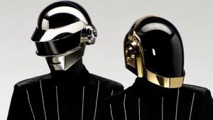 Na foto, destacando o fim da dupla Daft Punk, aparecem duas pessoas com capacetes. A do lado esquerdo está mais atrás vestindo um capacete prata, enquanto a da direita, mais à frente, está usando um capacete dourado.