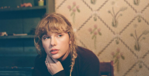 taylor swift em imagem de divulgação do album folklore, sentada e com uma trança de lado imagem ilustrativa do texto sobre taylor swift estar regravando seus álbuns