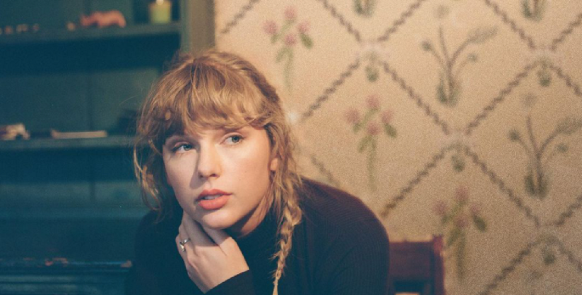 taylor swift em imagem de divulgação do album folklore, sentada e com uma trança de lado imagem ilustrativa do texto sobre taylor swift estar regravando seus álbuns