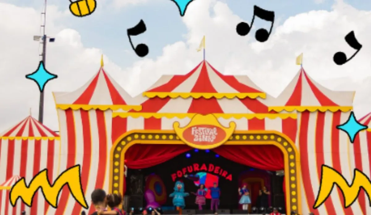 Palco em formato de circo do Festivalzinho, com fachada listrada em vermelho e branco, adornada com letreiro amarelo e cortinas vermelhas; no palco, personagens infantis se apresentam diante do público.