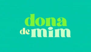 A imagem apresenta a frase "dona de mim" em uma fonte estilizada. As palavras estão exibidas em um fundo azul-petróleo. A palavra "dona" está em verde claro, "de" em pêsseg claro e "mim" em menta clara.