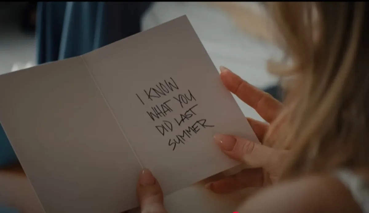 Cartão com a frase “I Know What You Did Last Summer” sendo segurado por uma mulher, em cena do trailer do remake de "Eu Sei o Que Vocês Fizeram no Verão Passado" (2025)
