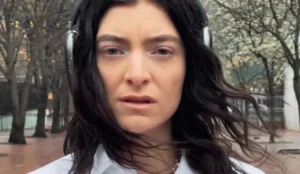 Lorde no clipe de "What Was That", novo single lançado em 2025. A imagem mostra a cantora com fones de ouvido em um cenário urbano