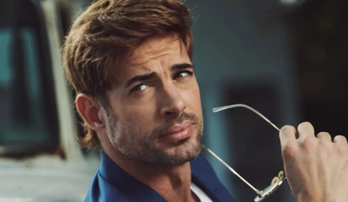 William Levy com expressão séria, segurando óculos de sol, em imagem promocional; ator foi preso nos EUA por três crimes em abril de 2025.