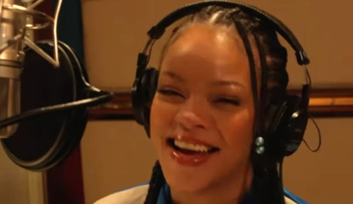 Rihanna sorrindo em estúdio de gravação enquanto dubla e canta para o novo filme dos Smurfs, que contará com sua nova música “Friend of Mine”.