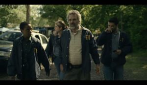 Cena da série Task, da HBO Max, mostra agentes do FBI caminhando em uma área arborizada durante uma investigação, com clima tenso e atmosfera policial.