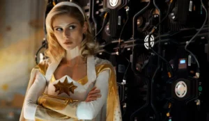 Erin Moriarty caracterizada como Starlight em "The Boys", usando seu uniforme branco e dourado com estrelas douradas no peito, em cena tensa diante de um painel tecnológico