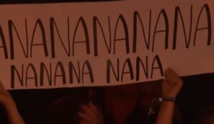 Fã com um cartaz onde se lê "nananana", do refrão de "Freed From Desire"