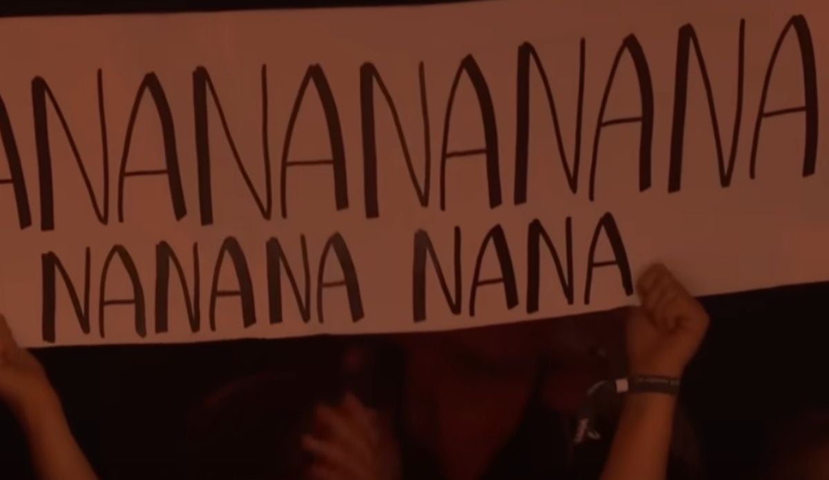 Fã com um cartaz onde se lê "nananana", do refrão de "Freed From Desire"