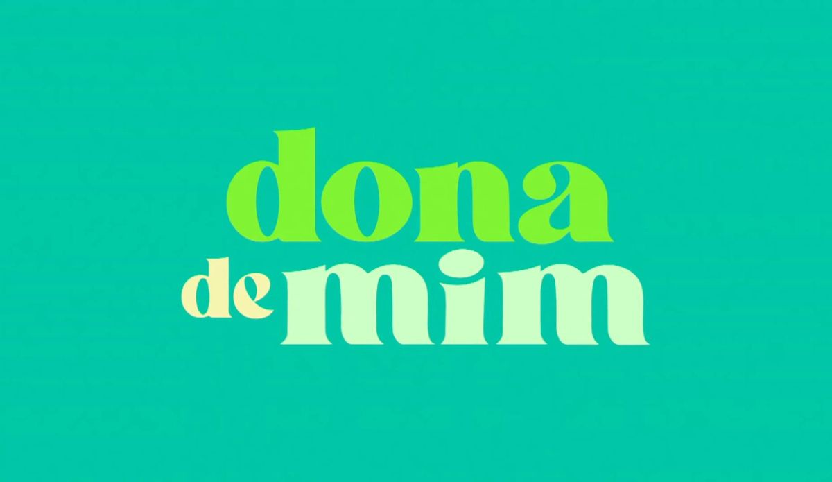 A imagem apresenta a frase "dona de mim" em uma fonte estilizada. As palavras estão exibidas em um fundo azul-petróleo. A palavra "dona" está em verde claro, "de" em pêsseg claro e "mim" em menta clara.