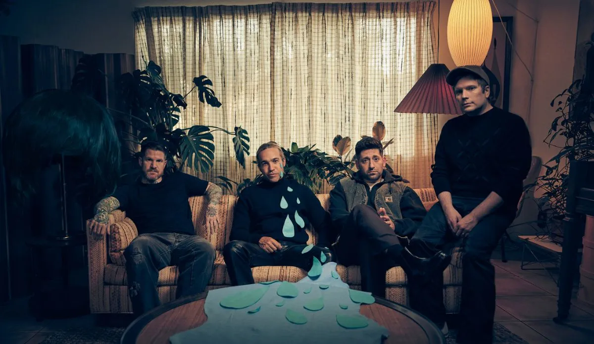 Foto da banda Fall Out Boy sentada em um sofá, com iluminação suave e elementos decorativos retrô.