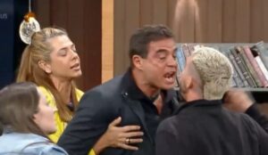 Dhomini grita exaltado durante briga com Radamés no Power Couple Brasil 7, enquanto outros participantes tentam contê-lo; momento tenso da confusão exibida no reality show da Record.