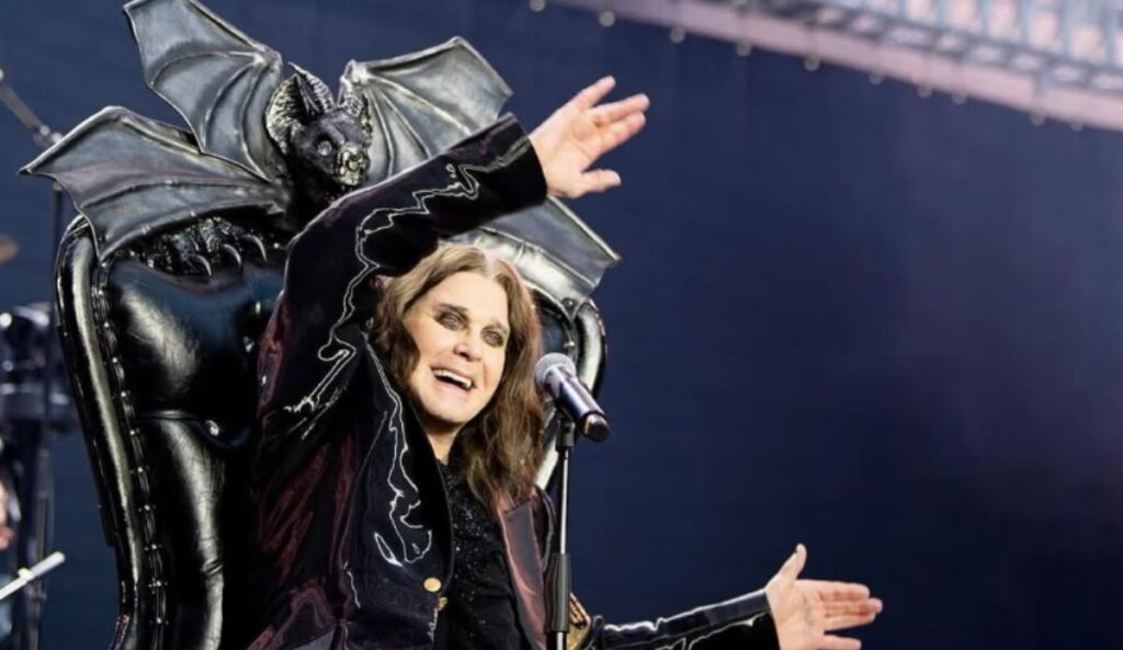 Ozzy Osbourne sorri e acena durante último show do Black Sabbath, sentado em trono decorado com morcegos no palco do tributo "Back to the Beginning", em Birmingham.