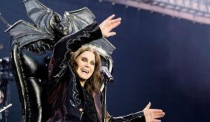Ozzy Osbourne sorri e acena durante último show do Black Sabbath, sentado em trono decorado com morcegos no palco do tributo "Back to the Beginning", em Birmingham.