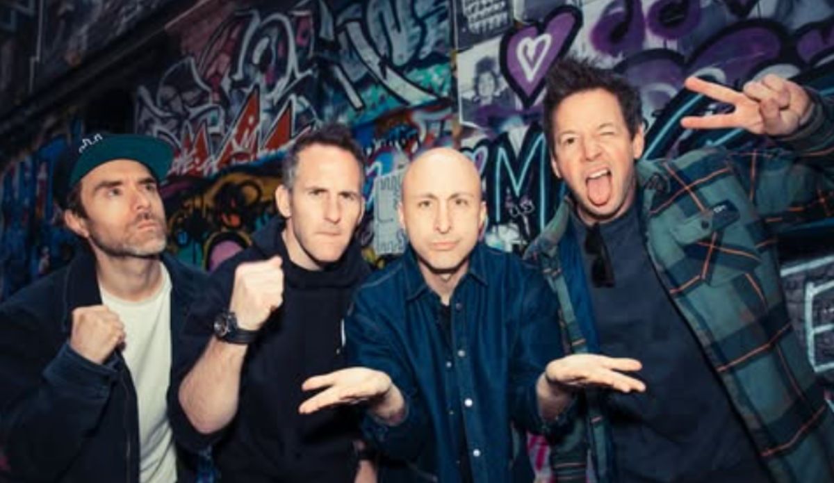 Integrantes do Simple Plan posam em frente a muro grafitado