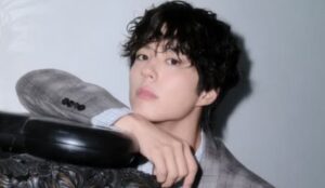 Park Bo Gum posa com olhar sério, vestindo blazer xadrez cinza e camisa clara