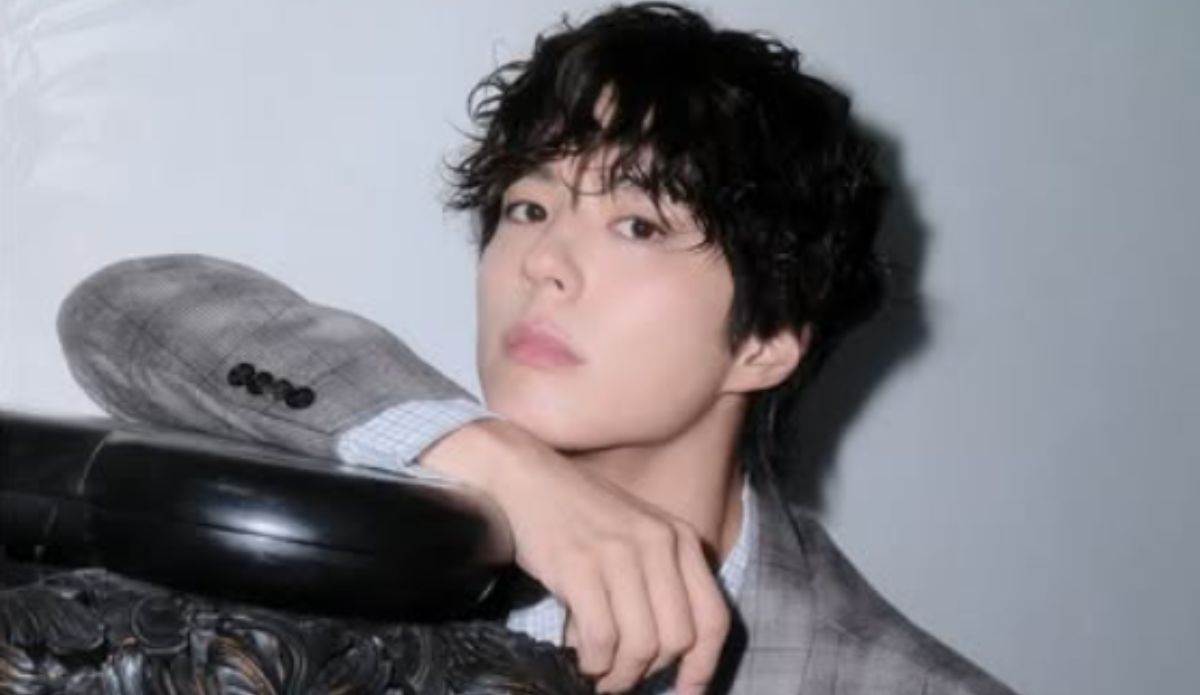 Park Bo Gum posa com olhar sério, vestindo blazer xadrez cinza e camisa clara