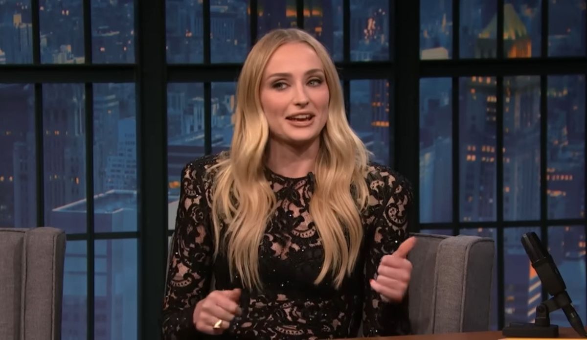 Sophie Turner durante entrevista no programa Late Night With Seth Meyers, usando vestido preto rendado e falando sobre novo filme.