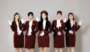 Integrantes do grupo de K-pop ARTMS posam lado a lado com uniformes vinho, luvas brancas e acenos, em foto promocional