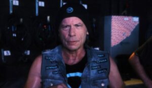 Bruce Dickinson, vocalista do Iron Maiden, usando gorro preto e colete jeans com patches de países em foto de bastidores de sua turnê "The Mandrack Projetc"; cantor se apresentou no The Town 2025.