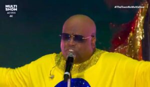 CeeLo Green se apresenta no The Town 2025, usando figurino amarelo brilhante com detalhes dourados, óculos escuros e cantando no microfone durante transmissão ao vivo do Multishow.