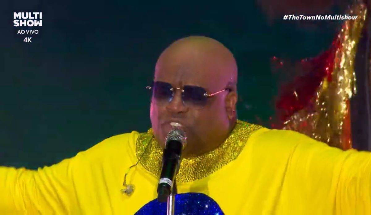 CeeLo Green se apresenta no The Town 2025, usando figurino amarelo brilhante com detalhes dourados, óculos escuros e cantando no microfone durante transmissão ao vivo do Multishow.