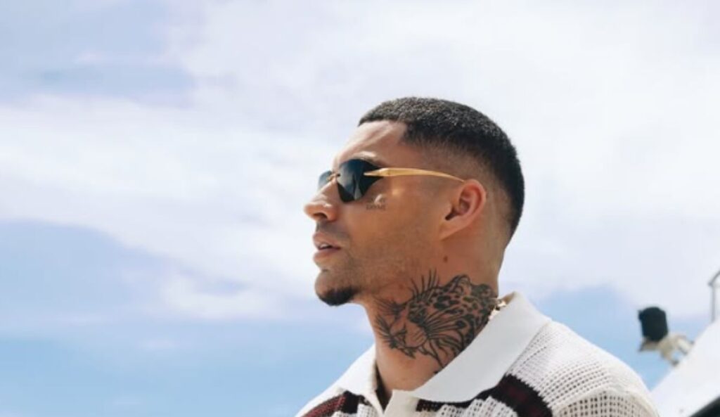 Filipe Ret de óculos escuros e camisa polo branca listrada, com tatuagem no pescoço, posa ao ar livre; artista se apresenta no The Town 2025, neste sábado (6), no palco Skyline.