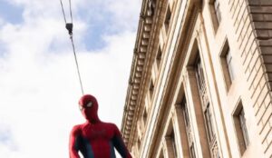 Homem-Aranha pendurado por cabos durante gravações de Homem-Aranha 4 em prédio de grande altura.