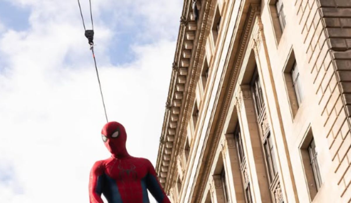 Homem-Aranha pendurado por cabos durante gravações de Homem-Aranha 4 em prédio de grande altura.