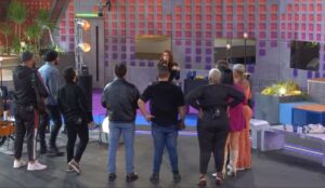 Participantes do reality Estrela da Casa assistem à apresentadora Ana Clara, que aparece no centro do palco durante uma festa surpresa no Centro de Treinamento.