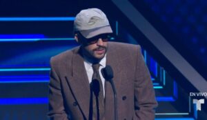 Bad Bunny durante seu discurso de agradecimento no Billboard Latin Music Awards 2025, em Miami, usando terno marrom, boné e óculos escuros