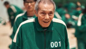 Oh Yeong-su em cena de Round 6, vestindo uniforme verde com o número 001, personagem marcante da série sul-coreana da Netflix.