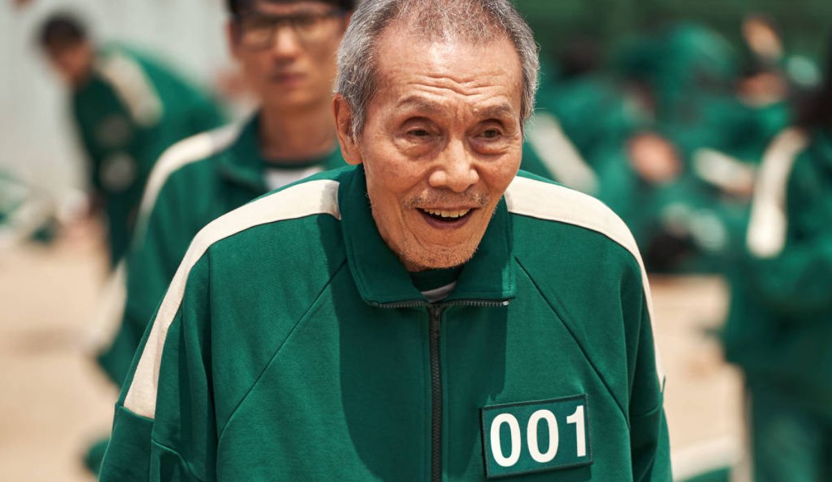 Oh Yeong-su em cena de Round 6, vestindo uniforme verde com o número 001, personagem marcante da série sul-coreana da Netflix.