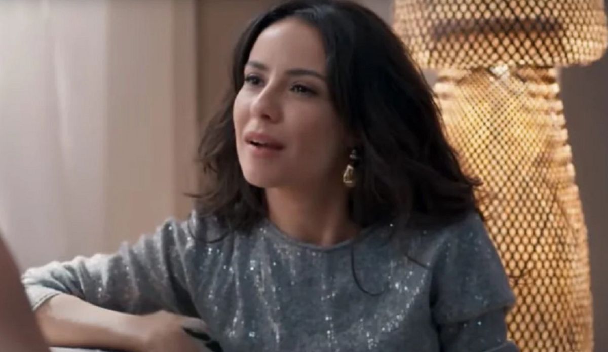 Cena de Três Graças mostra Zenilda sentada, usando blusa cinza brilhante, em momento de tensão na novela.