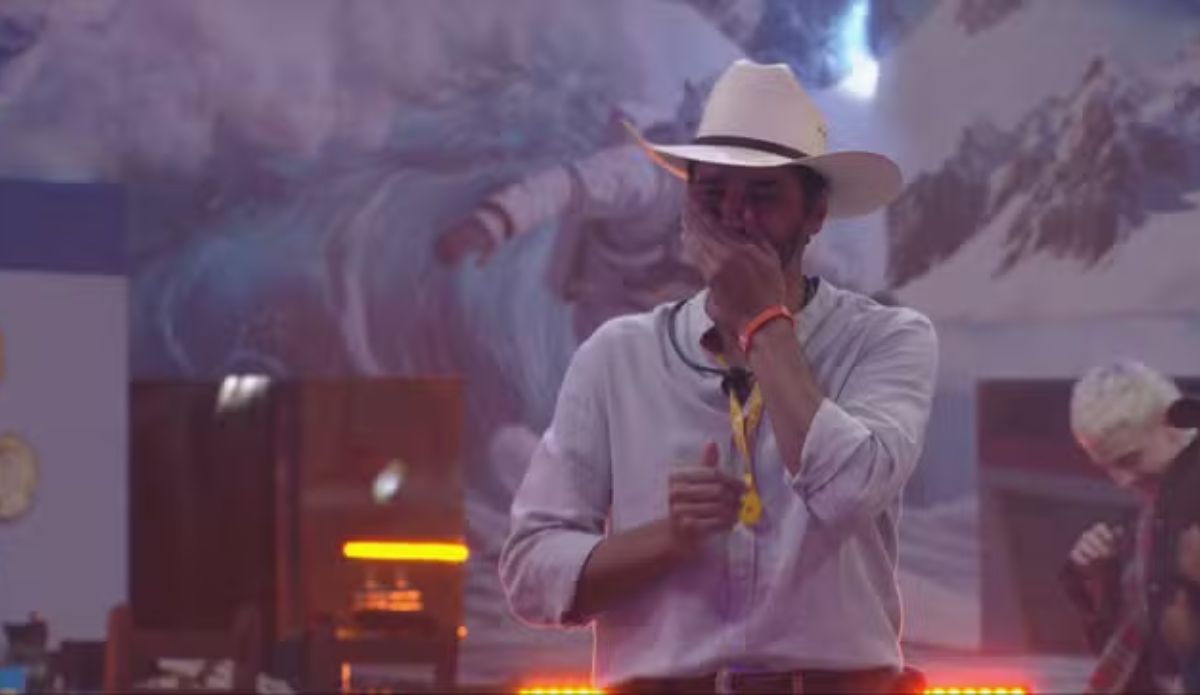 Alberto Cowboy durante sua festa do Líder no BBB 26, usando chapéu e cobrindo o rosto emocionado