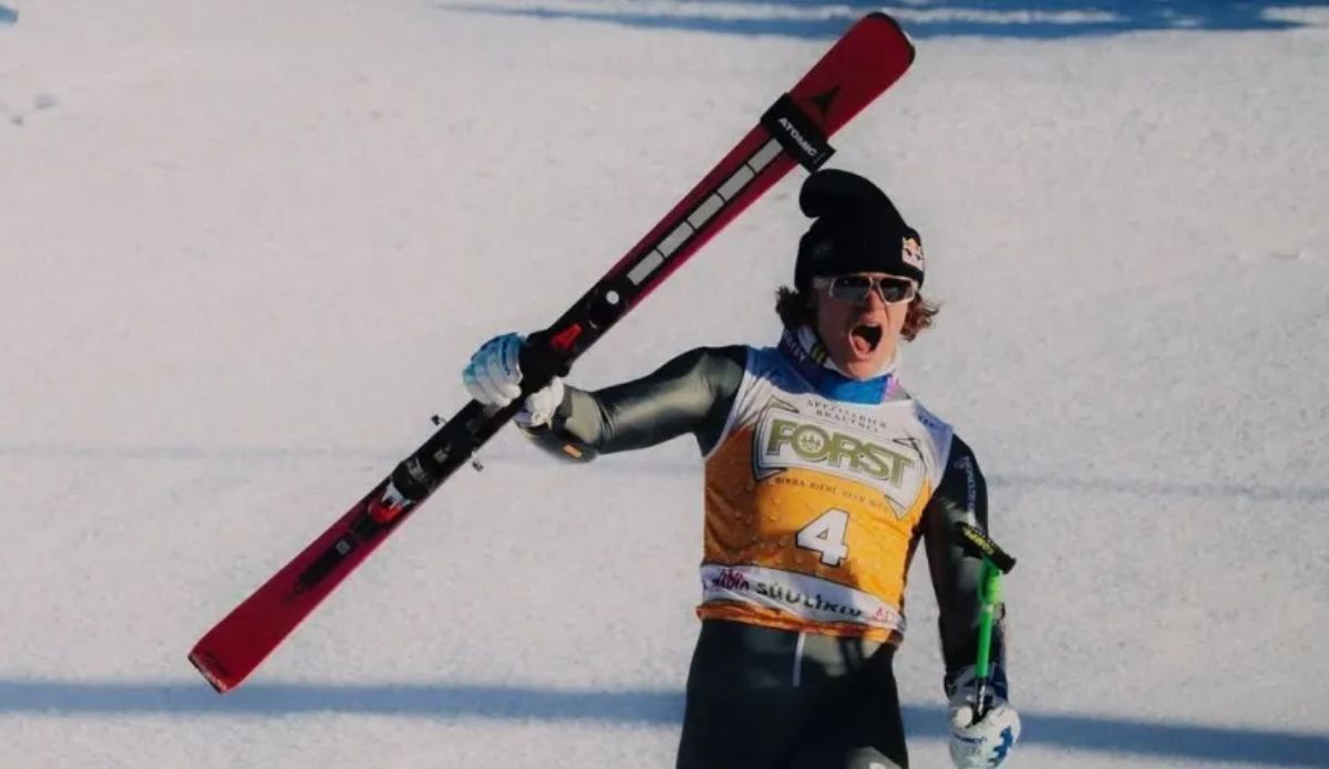 Lucas Pinheiro Braathen, atleta de esqui alpino celebra na neve erguendo os esquis durante prova; ele está presente nos Jogos Olímpicos de Inverno 2026.