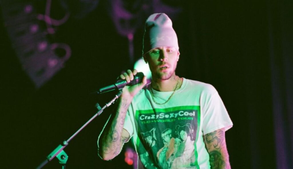 Justin Bieber segurando microfone durante apresentação com iluminação verde no palco; artista é headliner do Coachella 2026