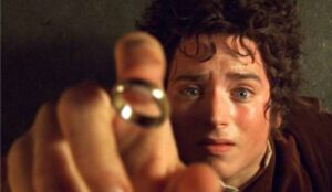 Frodo segura o Um Anel em cena de O Senhor dos Anéis: A Sociedade do Anel, mostrando expressão de tensão e impacto diante do objeto