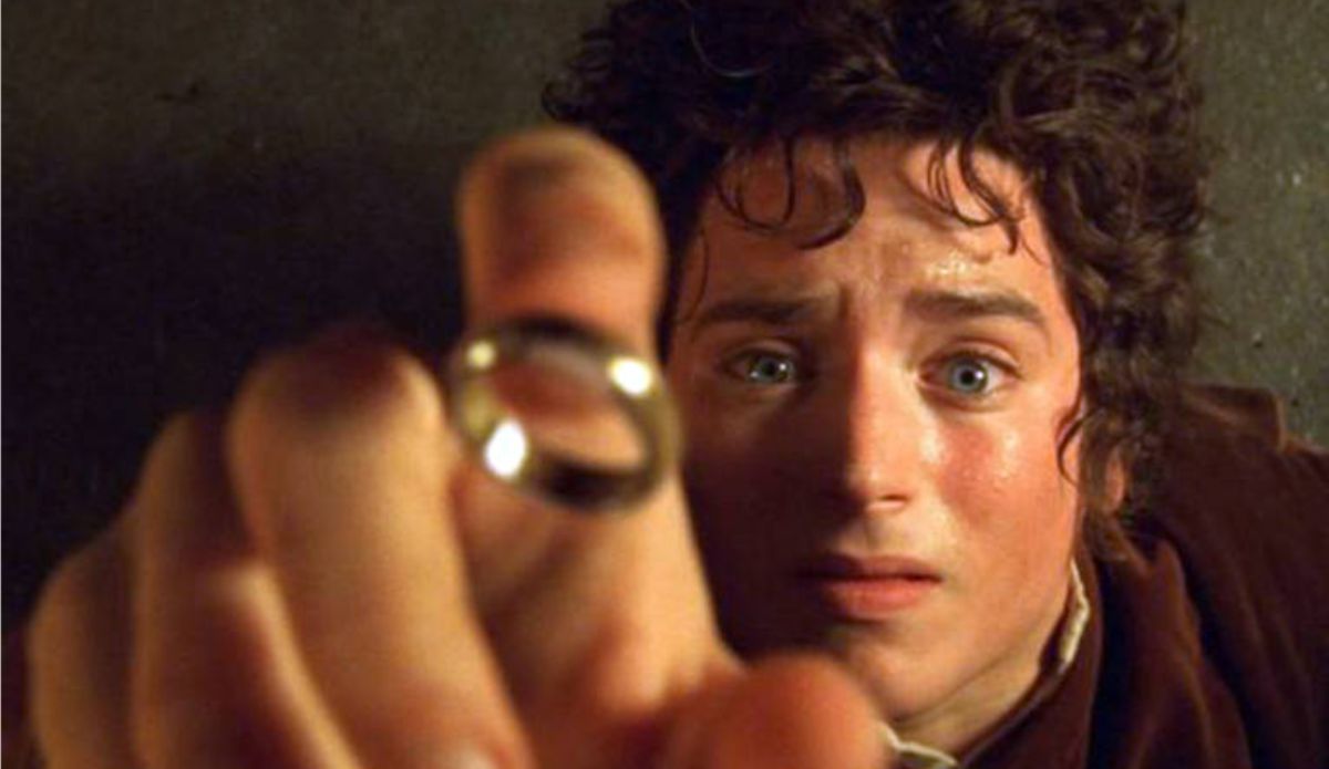 Frodo segura o Um Anel em cena de O Senhor dos Anéis: A Sociedade do Anel, mostrando expressão de tensão e impacto diante do objeto