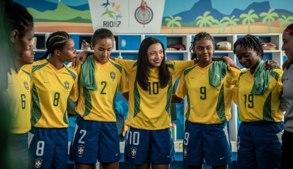 Alice Carvalho caracterizada como Marta ao lado de jogadoras da seleção brasileira em cena da cinebiografia