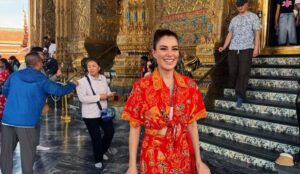 Ece İrtem sorrindo em frente a templo dourado durante viagem à Tailândia.