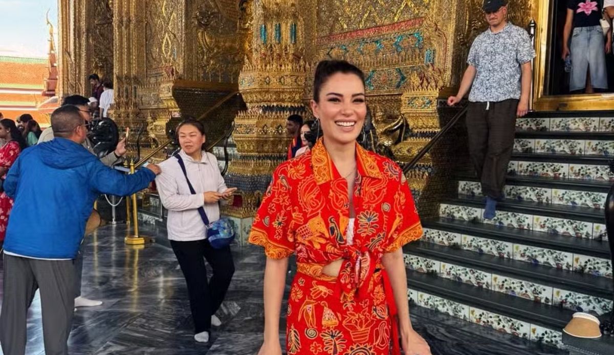 Ece İrtem sorrindo em frente a templo dourado durante viagem à Tailândia.