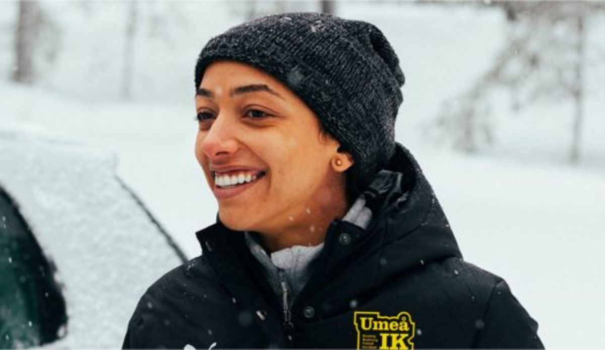 Alice Carvalho caracterizada como Marta durante as gravações da cinebiografia da Rainha do Futebol, usando gorro e casaco preto em cenário coberto de neve na Suécia.